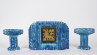 une horloge bleue posée à côté de deux bougies et d'un bougeoir