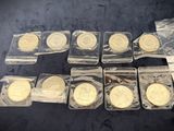 several gold and silver coins in plastic bags on a black surface