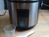 a crock pot with a spoon next to it on a table