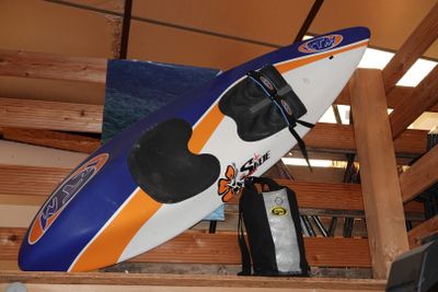 un kayak bleu et orange posé sur une étagère en bois