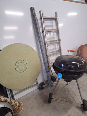 a large black grill sitting in a garage next to a ladder