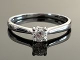 a close up of a diamond ring on a reflective surface