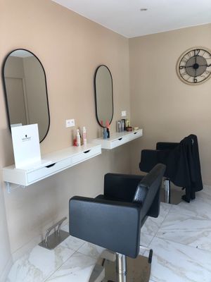 une photo d'un salon de coiffure avec des fauteuils et des miroirs