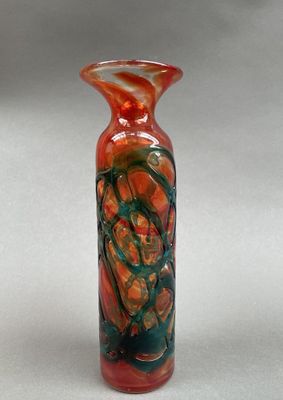 un vase rouge et vert posé sur une surface blanche