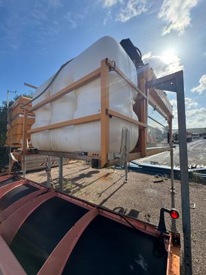 une photo montrant un grand réservoir en train d'être chargé sur un camion à plateau