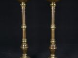 a pair of brass candlesticks with a white candle in the middle
