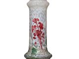 un vase en verre orné de fleurs rouges, posé sur une surface blanche