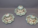 three pieces of porcelain pottery with flowers on them on a gray surface