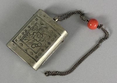 a silver flask with a red bead on a chain