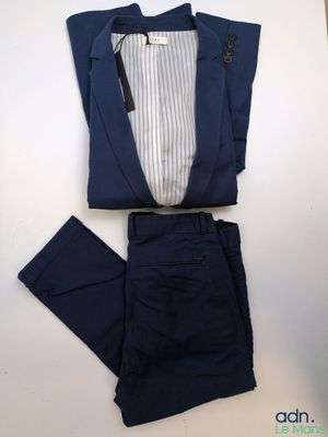 un costume bleu marine avec une chemise et un pantalon à rayures blanches, posé sur une table blanche