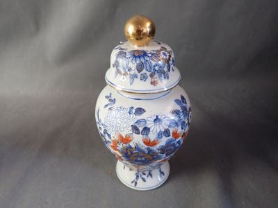 a blue and white vase with a gold lid