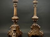 une paire de bougeoirs anciens en bois sculpté sur socles, sur fond sombre