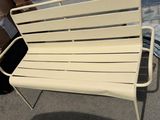 a white bench that is sitting on the sidewalk