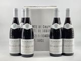 three bottles of red wine sit in front of a silver box