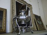 a silver tea pot sitting on top of a shelf next to pictures