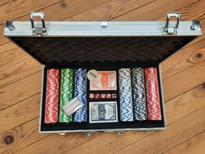 une valise contenant des jetons de poker et des cartes, posée sur un plancher en bois