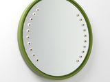 un miroir circulaire vert accroché à un mur blanc