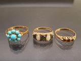 three rings with turquoise and yellow stones are on a table