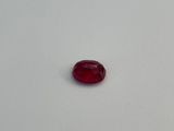 a red oval shaped stone on a white surface