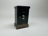 une petite horloge noire posée sur un socle, sur une surface blanche