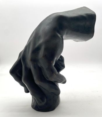 une sculpture noire représentant une main tenant quelque chose dans sa main droite