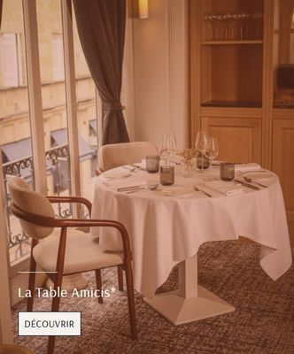 a table with a white table cloth on it and a chair in front of a window