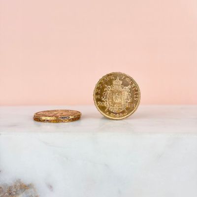 a gold coin sitting on top of a marble slab next to a gold coin