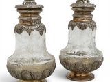 une paire de vases en argent et en verre posés sur des socles, sur fond blanc