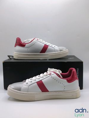 a pair of white and red sneakers sitting on top of a box