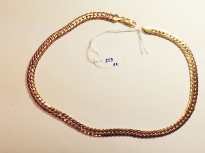 a close up of a gold chain bracelet on a white surface