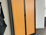 a coat rack in the corner of a room with a coat hanging on it