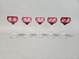 four wine glasses are lined up in a row on a white surface