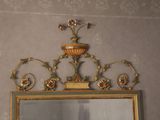 a mirror with a gold frame and a vase on top of it