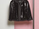 une veste noire suspendue à un porte-manteau près d'un mur rose et blanc