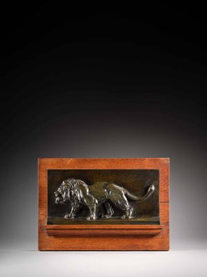 une plaque en bronze représentant un lion, posée sur un socle en bois