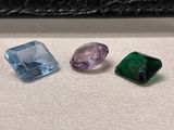 trois pierres précieuses de couleurs différentes posées sur une surface blanche