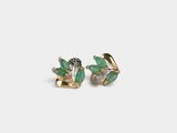a pair of earrings with green leaves and diamonds