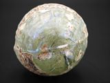a close up of a green and white ball on a black surface