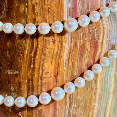 two strands of white pearls are on a wooden surface