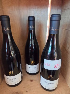 trois bouteilles de vin sont posées dans une caisse en bois sur une étagère