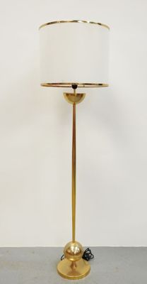 une lampe de table en laiton surmontée d'un abat-jour blanc