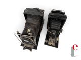 two old cameras are sitting side by side on a white surface