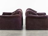 pair of purple velvet sofas with black legs and arms