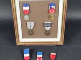three medals are displayed in a shadow box on a black background