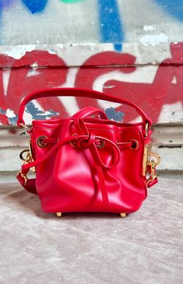 red leather bucket bag with gold hardwares on a concrete surface