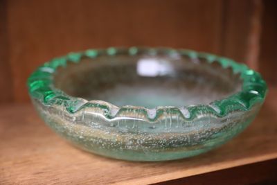 un bol en verre vert posé sur une étagère dans une pièce
