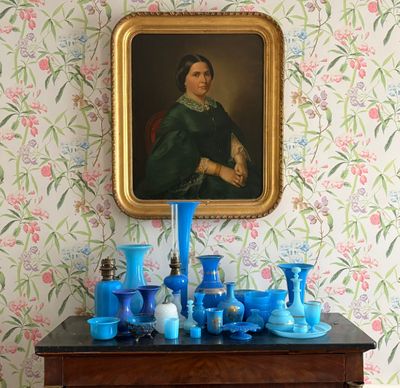 un tableau accroché au mur au-dessus d'une commode sur laquelle sont posés des vases bleus