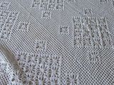 a white crocheted blanket on a bed