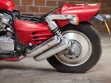 a red motorcycle that is parked in front of a brick wall
