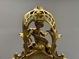 une horloge en or avec une femme assise dessus